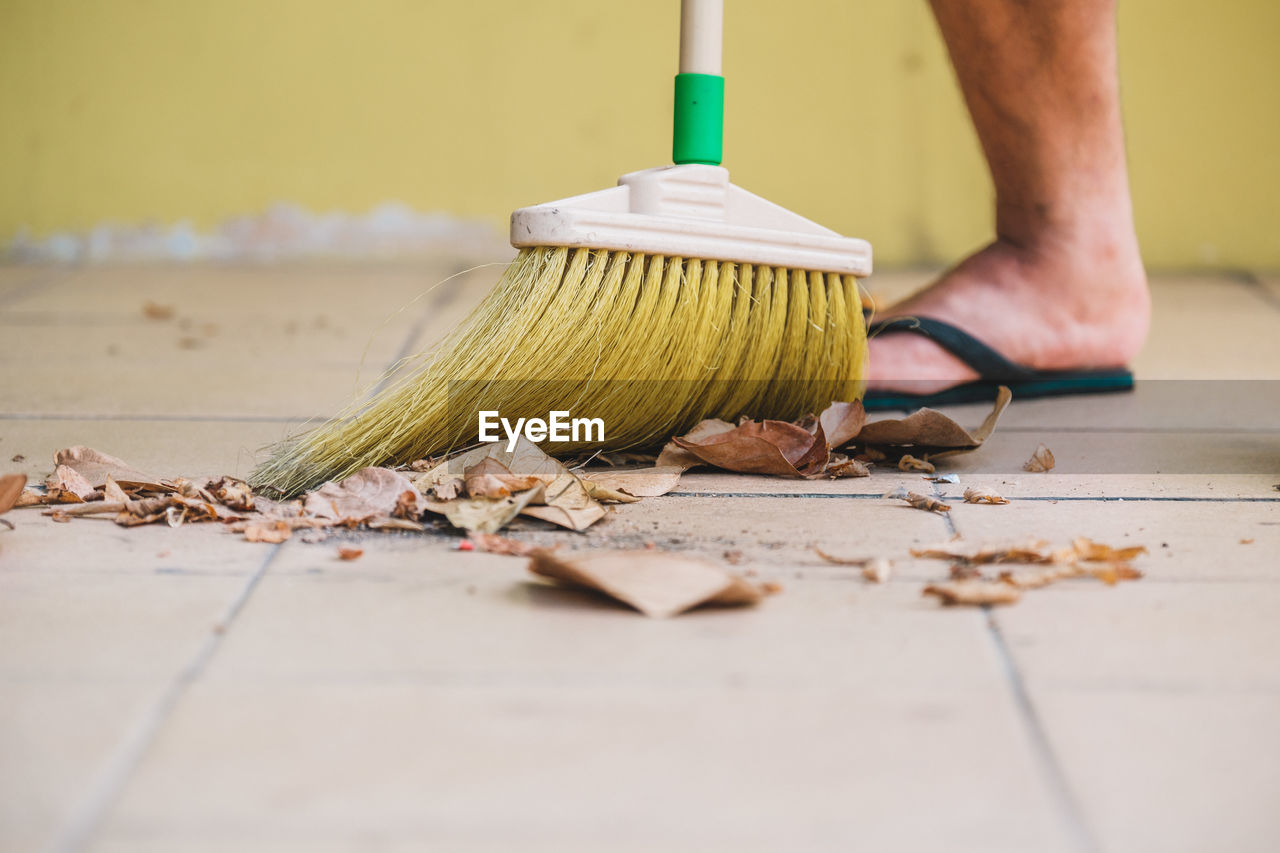 Low section of man cleaning floor with broom