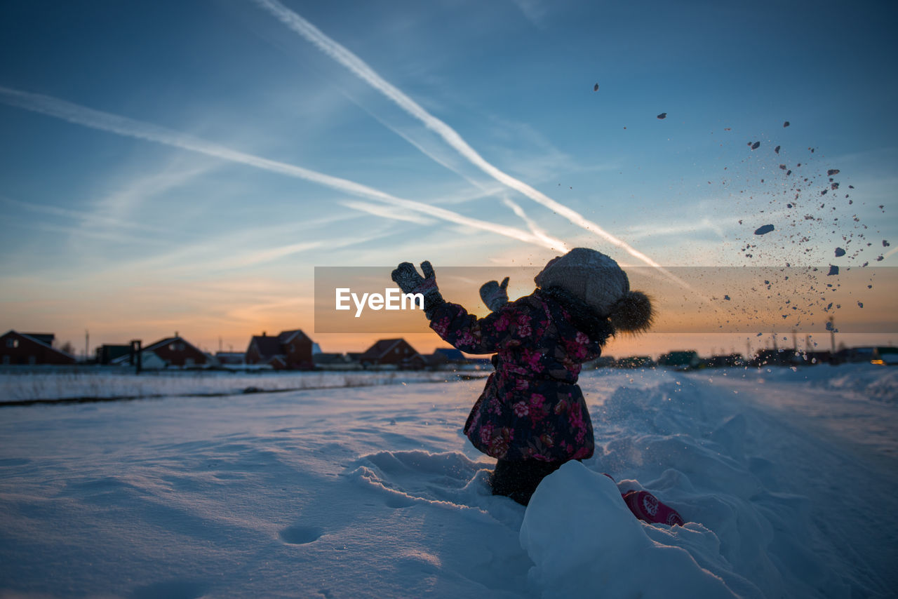 Full length of girl on snow covered land against sky during sunset