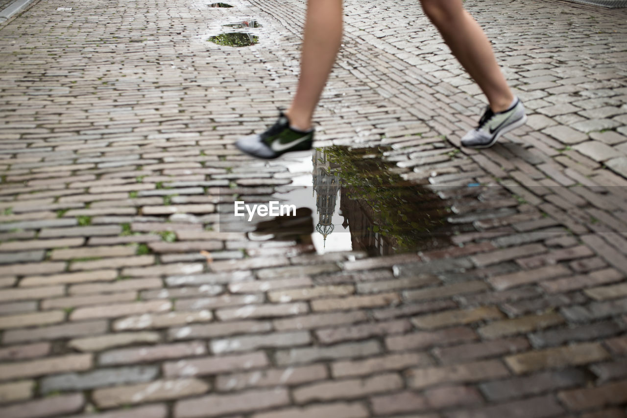 LOW SECTION OF WOMAN WALKING ON TILED FLOOR