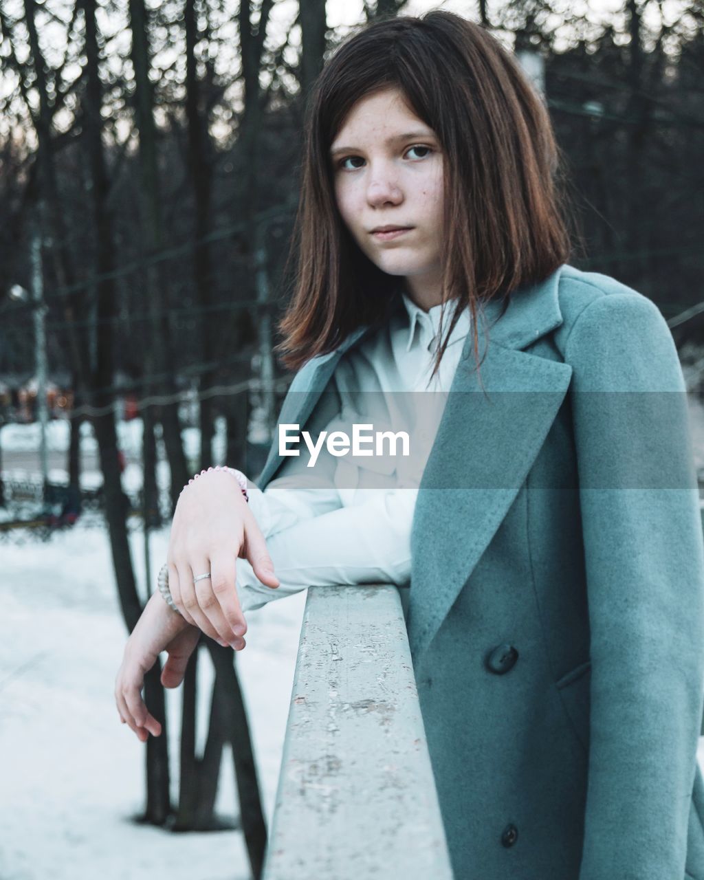 Portrait of beautiful young woman standing against trees