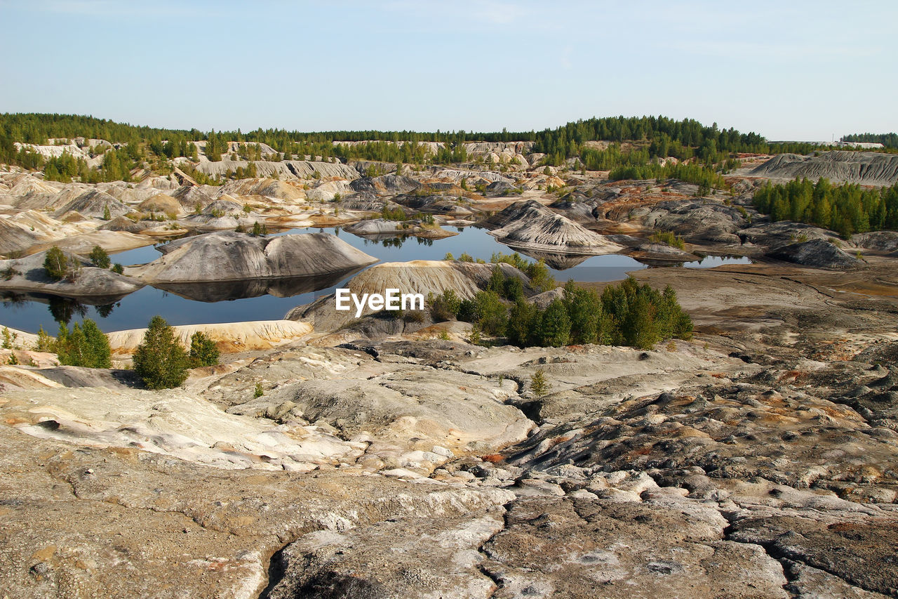 View on a flooded quarry with lakes and dried hills with rare vegetation.