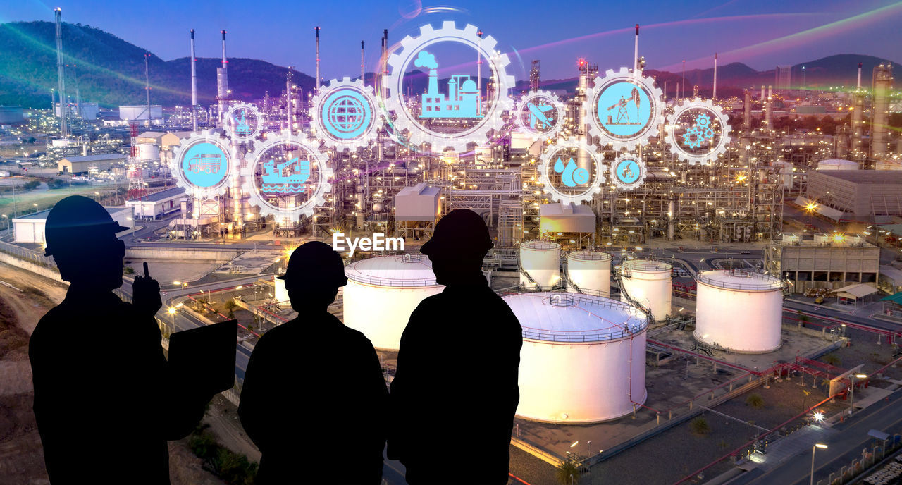 REAR VIEW OF PEOPLE STANDING IN ILLUMINATED AMUSEMENT PARK