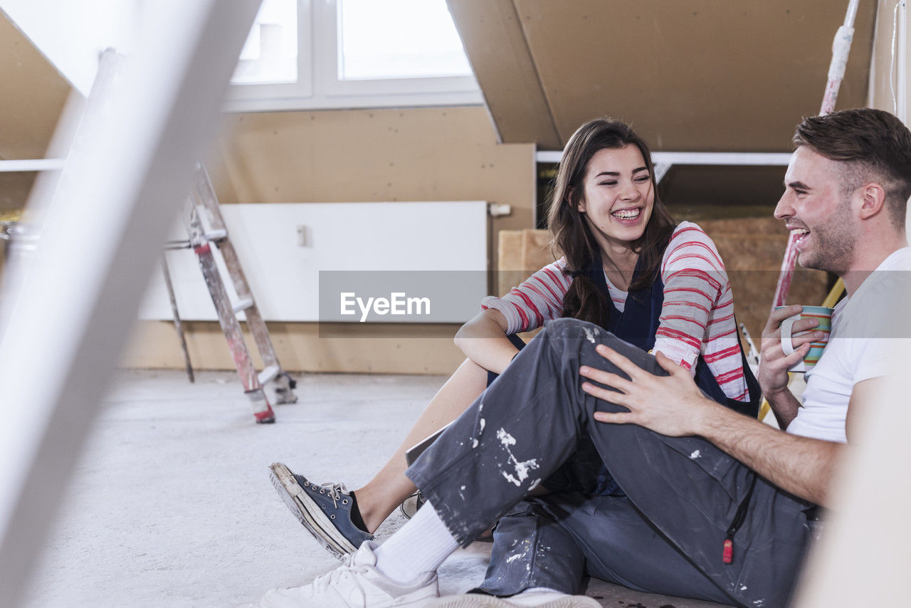 Happy young couple sitting and taking coffee break at home