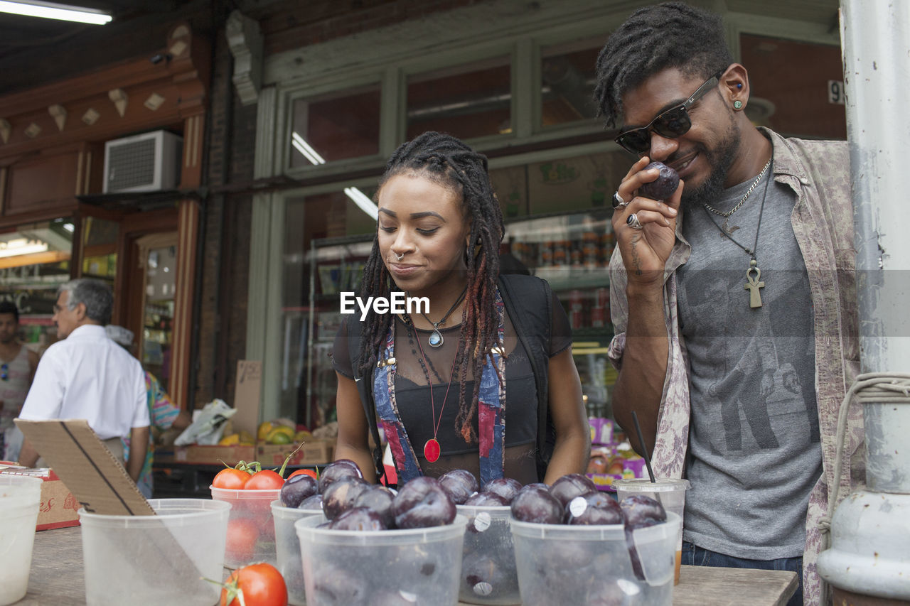 A young man and woman at a fruit stall.