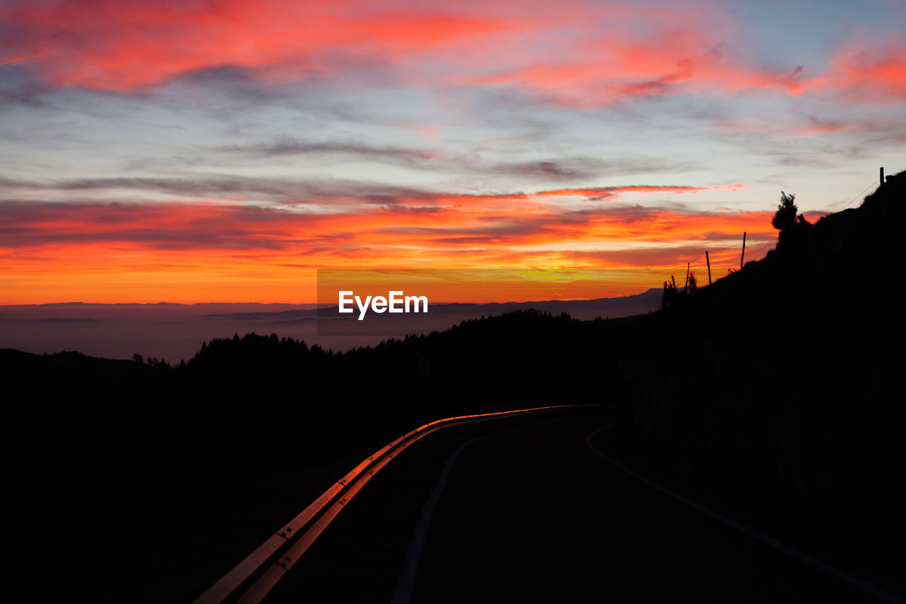 SILHOUETTE ROAD AGAINST ORANGE SKY DURING SUNSET