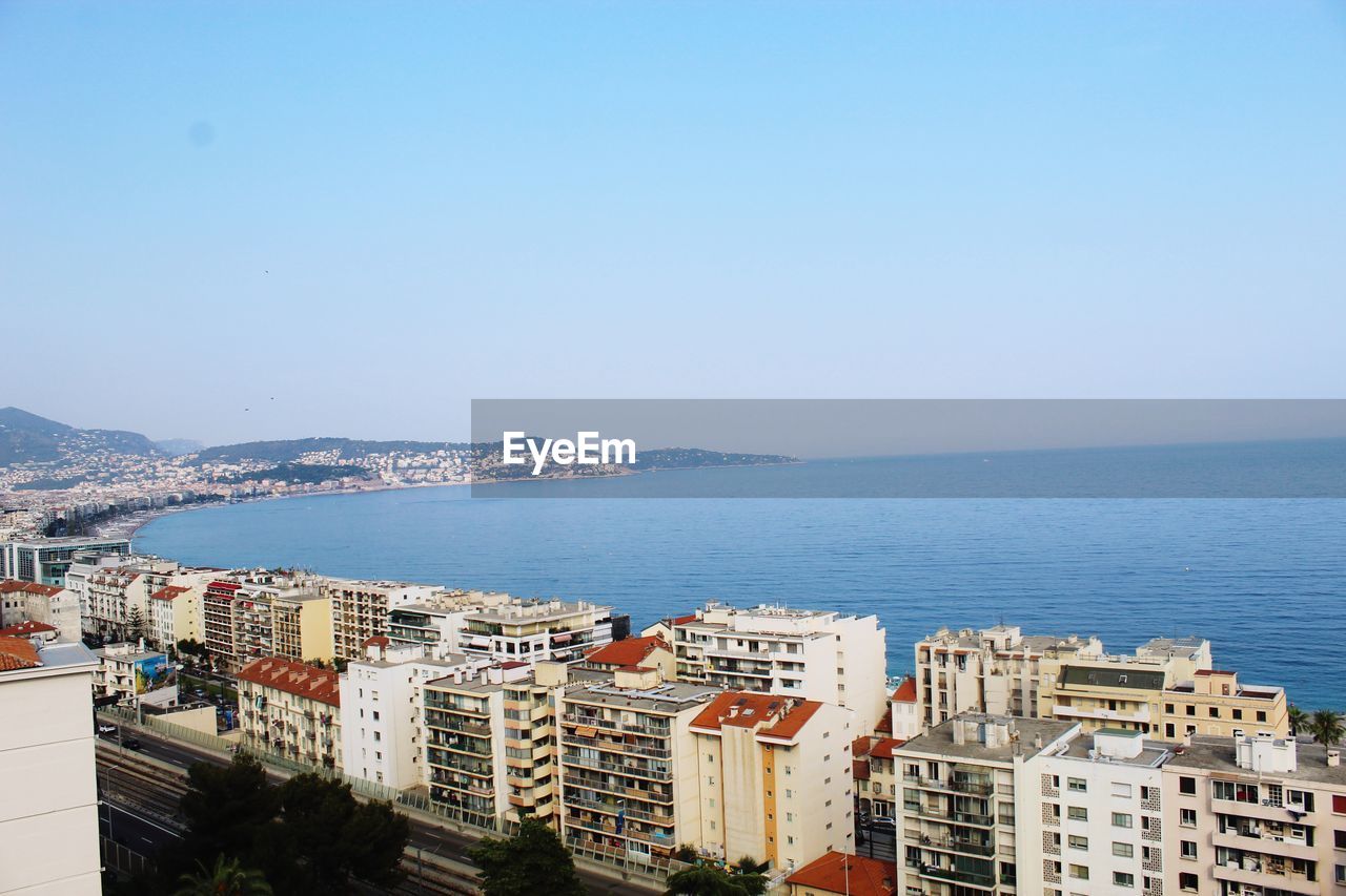 High angle view of townscape by sea against clear sky