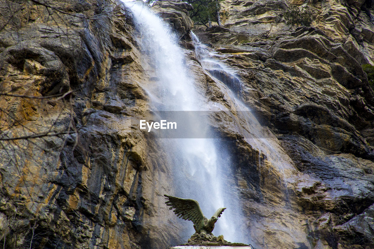 Bird sculpture against waterfall