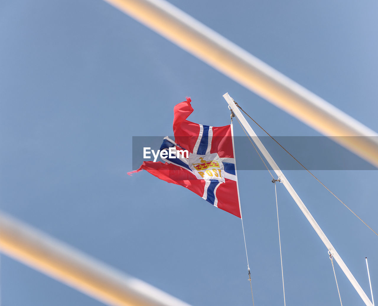 Low angle view of flag waving against clear blue sky