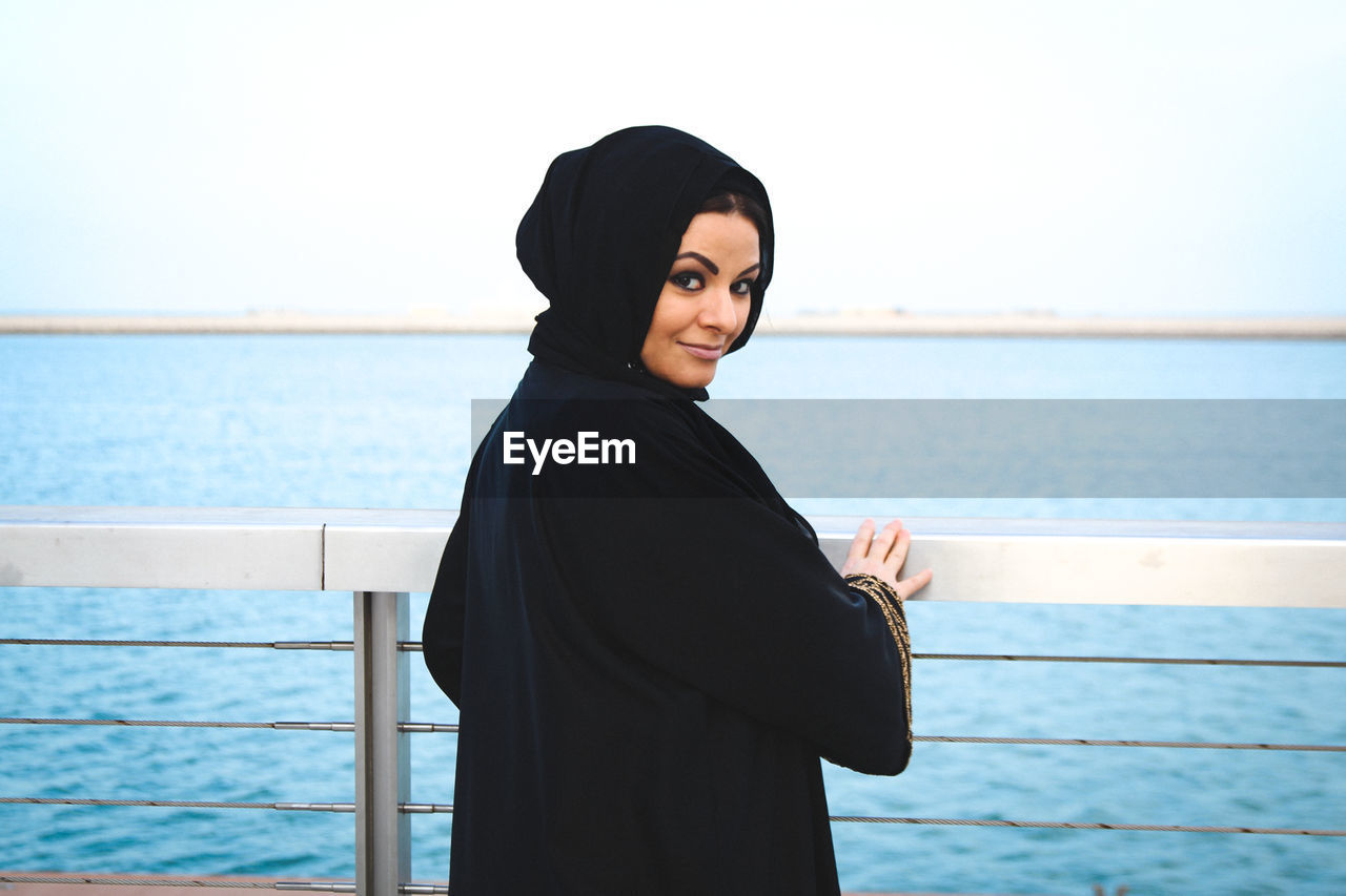 Woman standing by railing against sea