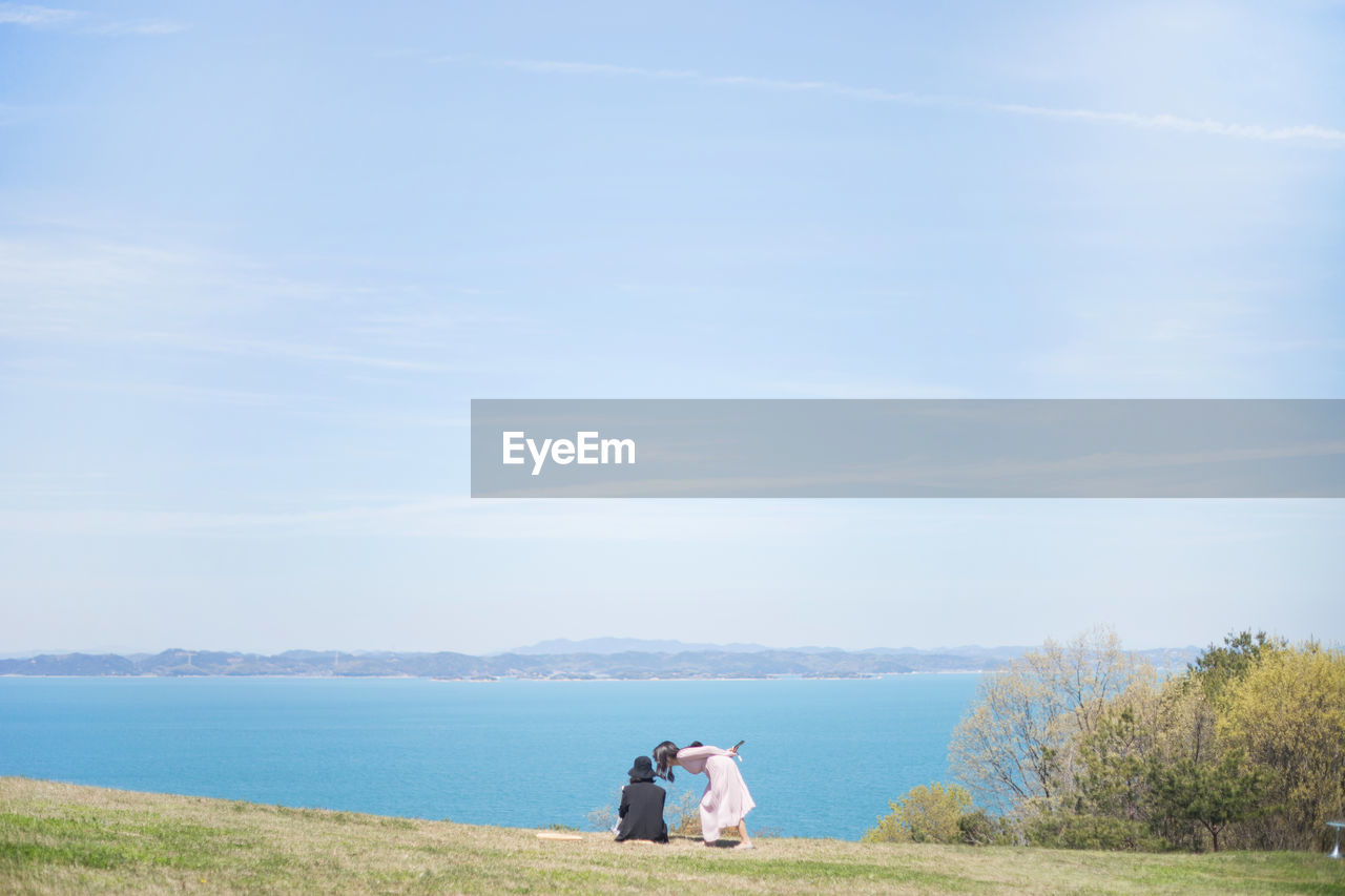 REAR VIEW OF MAN AND WOMAN STANDING AGAINST SKY