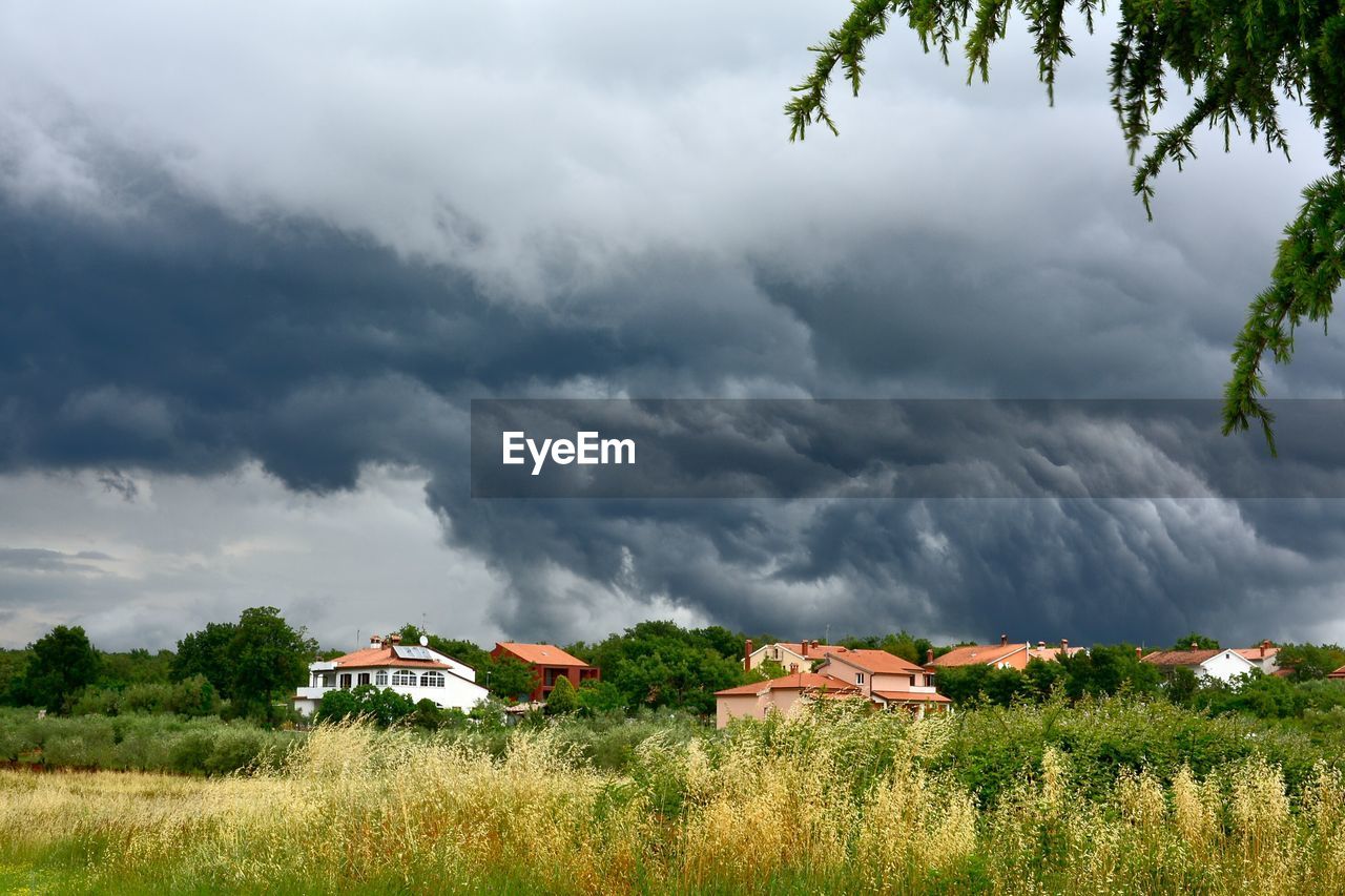 VIEW OF HOUSES ON LANDSCAPE AGAINST CLOUDY SKY