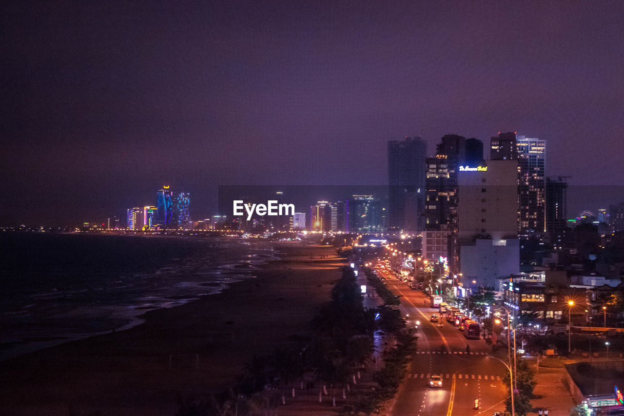 ILLUMINATED STREET AMIDST BUILDINGS AT NIGHT