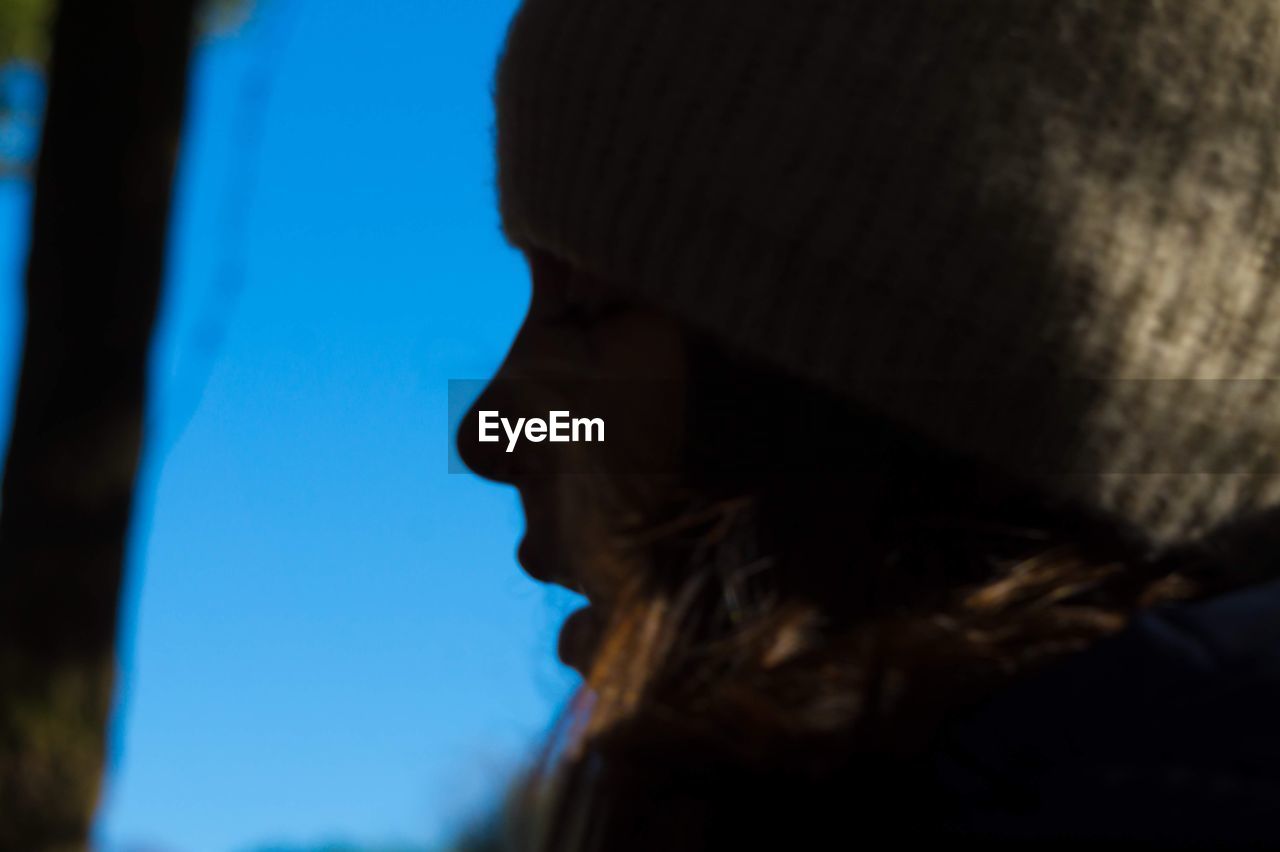 CLOSE-UP PORTRAIT OF YOUNG WOMAN AGAINST BLUE SKY