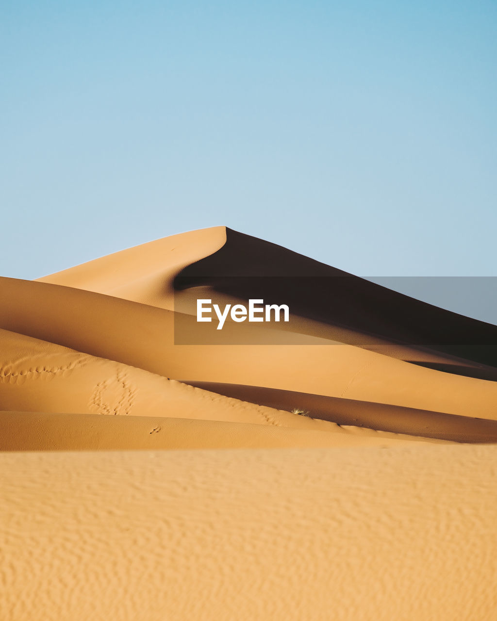 Low angle view of sand dunes against clear sky