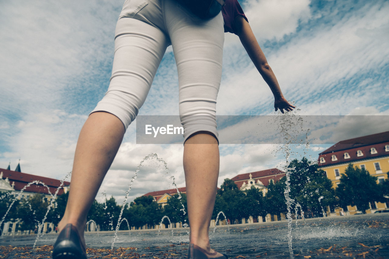 Low section of woman walking in city against sky