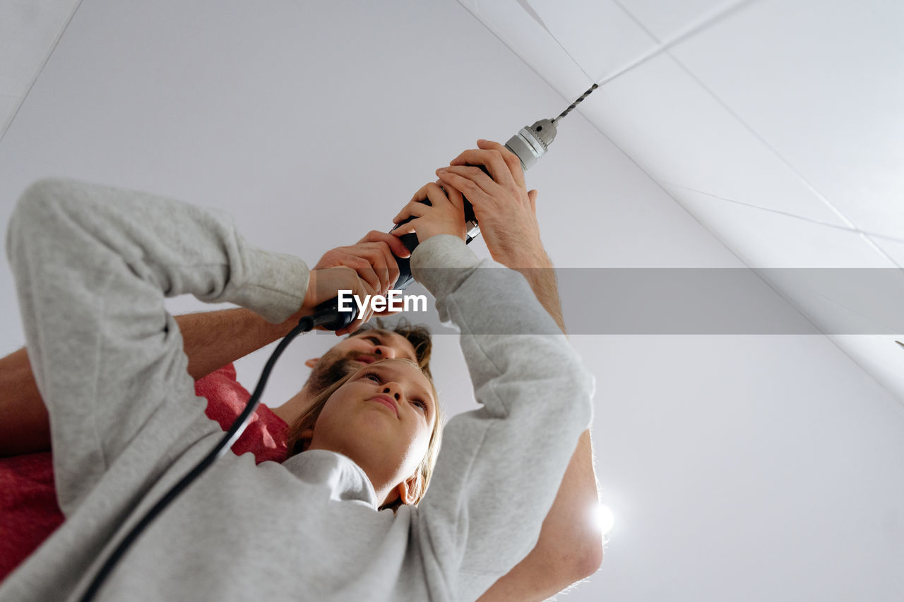 High angle view of father and daughter drilling the wall at home