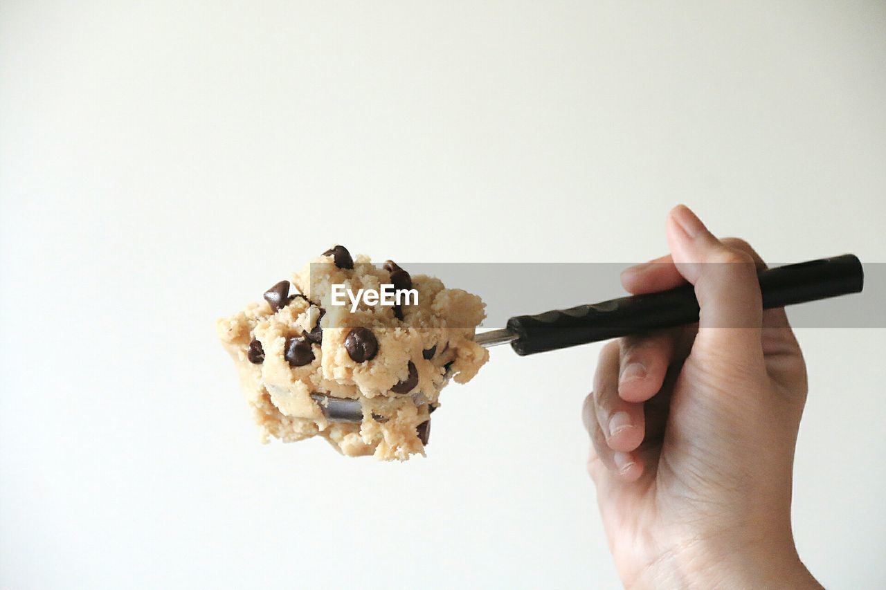 Close-up of hand holding cookies against white background