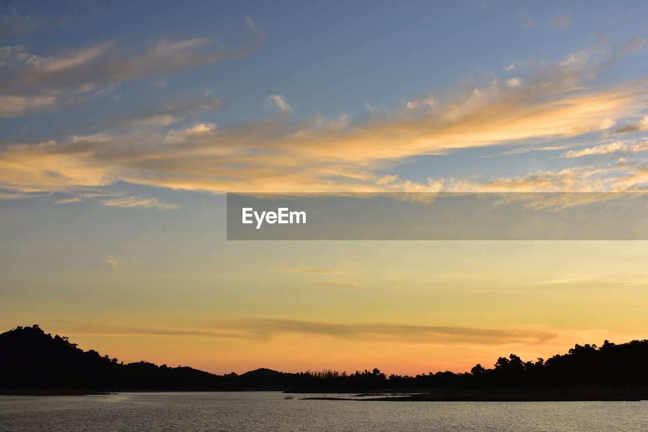 SILHOUETTE PLANTS BY LAKE AGAINST SKY DURING SUNSET