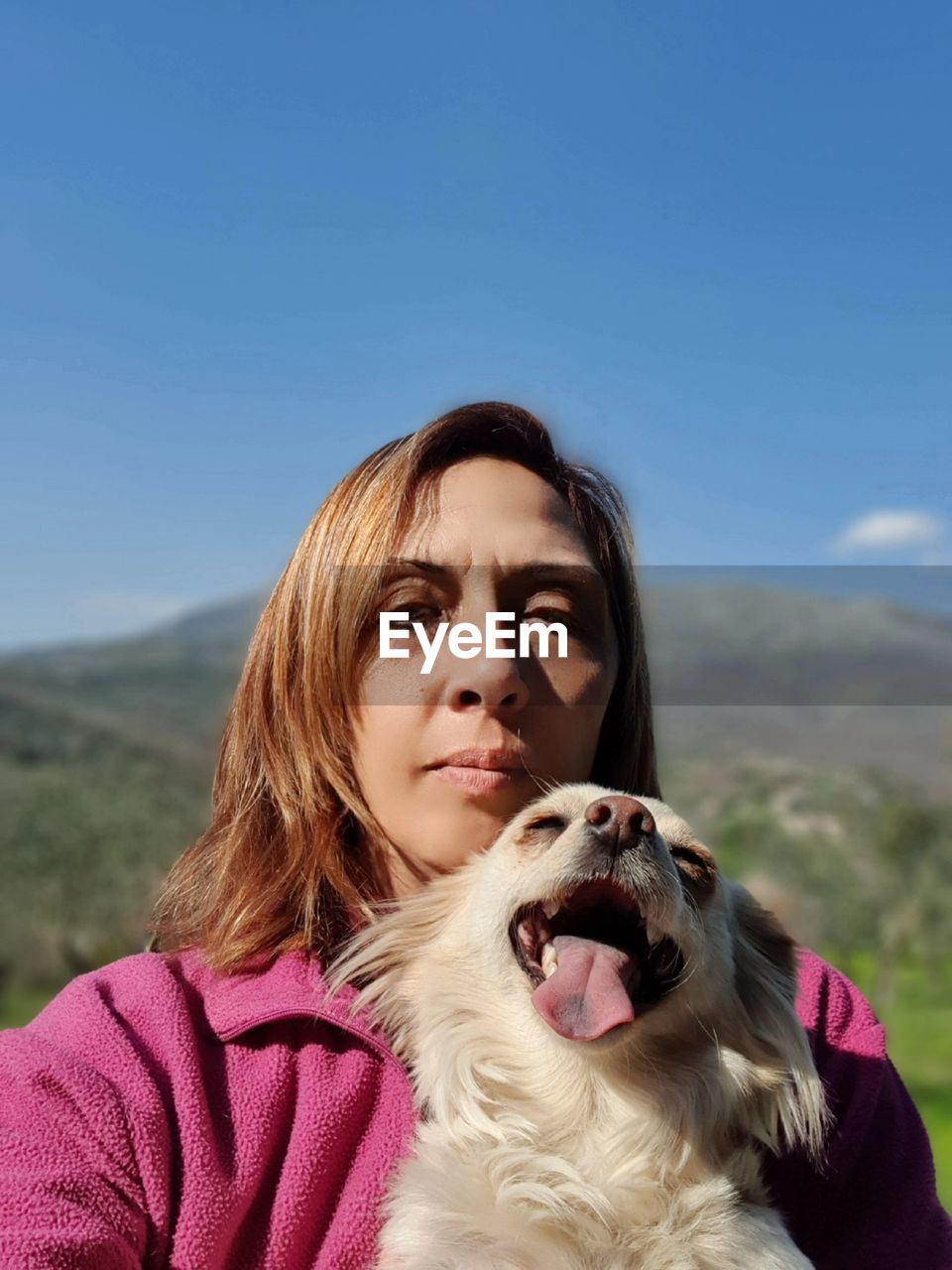 Portrait of woman with dog against sky