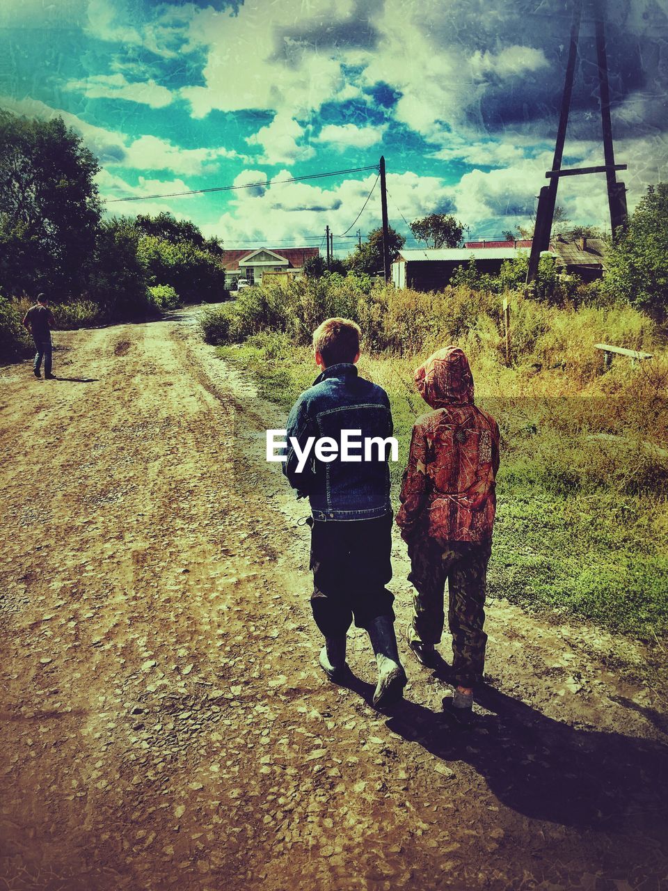 REAR VIEW OF TWO PEOPLE STANDING BY TREE