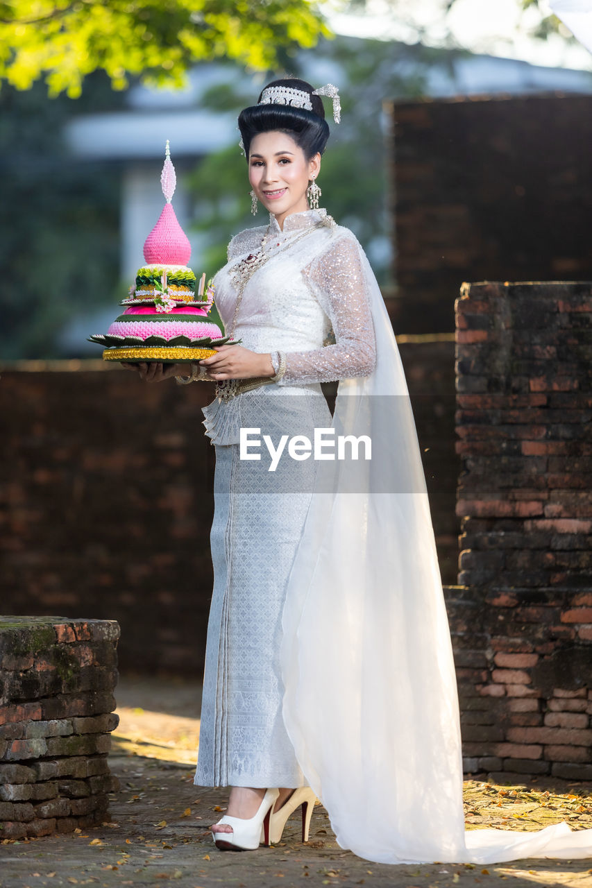 portrait of smiling young woman standing in traditional clothing walking at home
