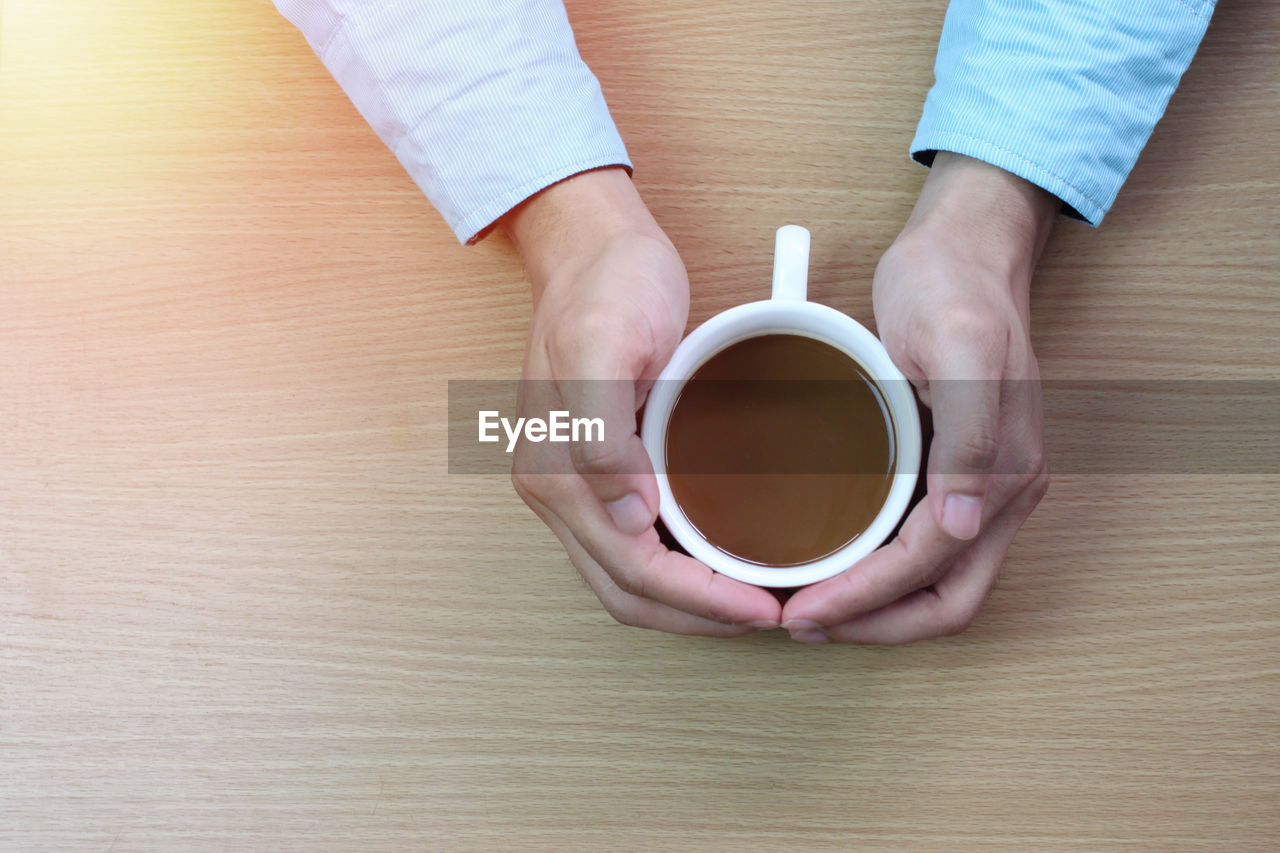 DIRECTLY ABOVE SHOT OF HAND HOLDING COFFEE CUP