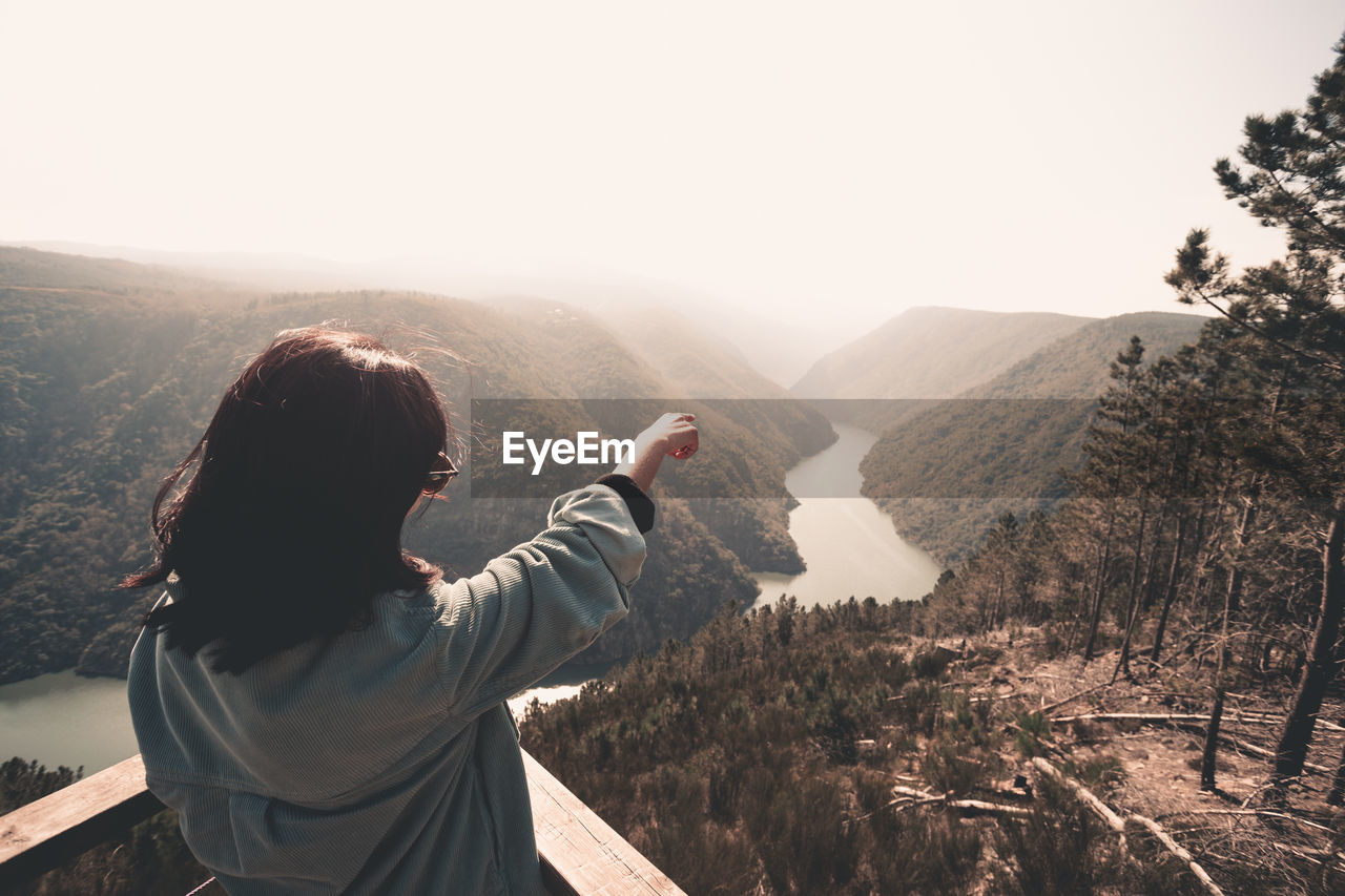 REAR VIEW OF MAN LOOKING AT MOUNTAINS