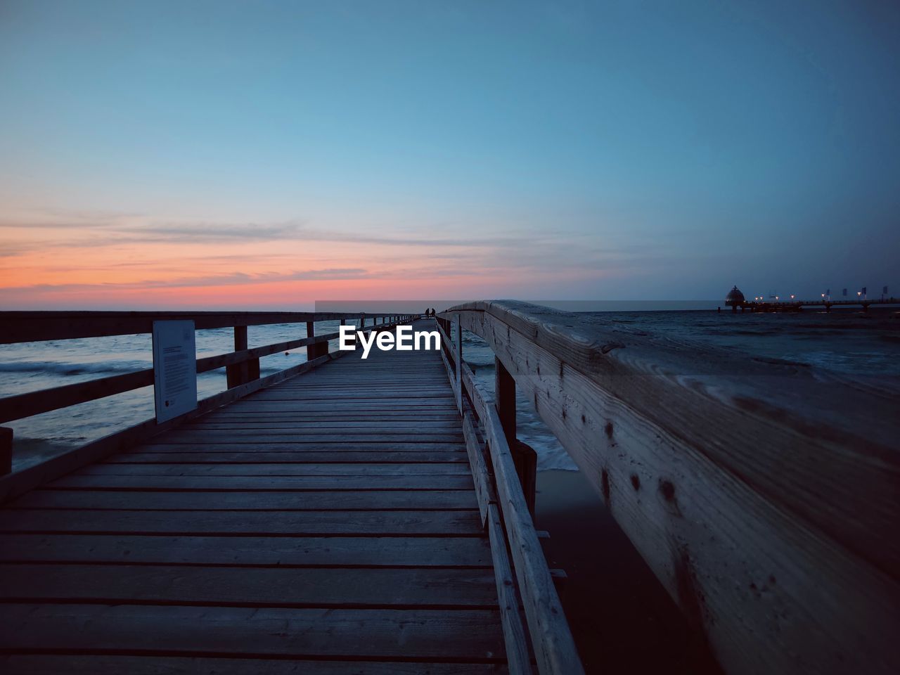 Pier over sea against sky during sunset