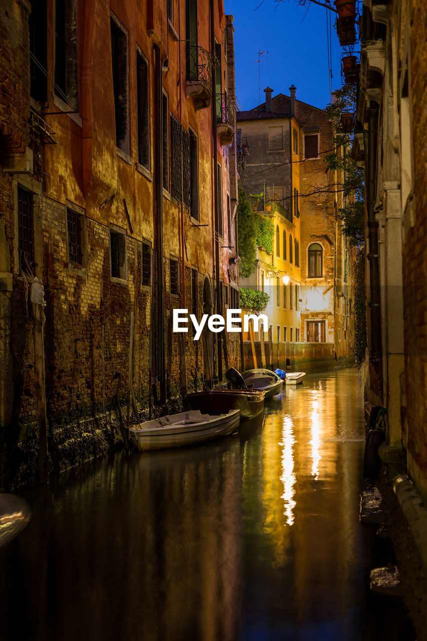 Canal amidst buildings in city at night