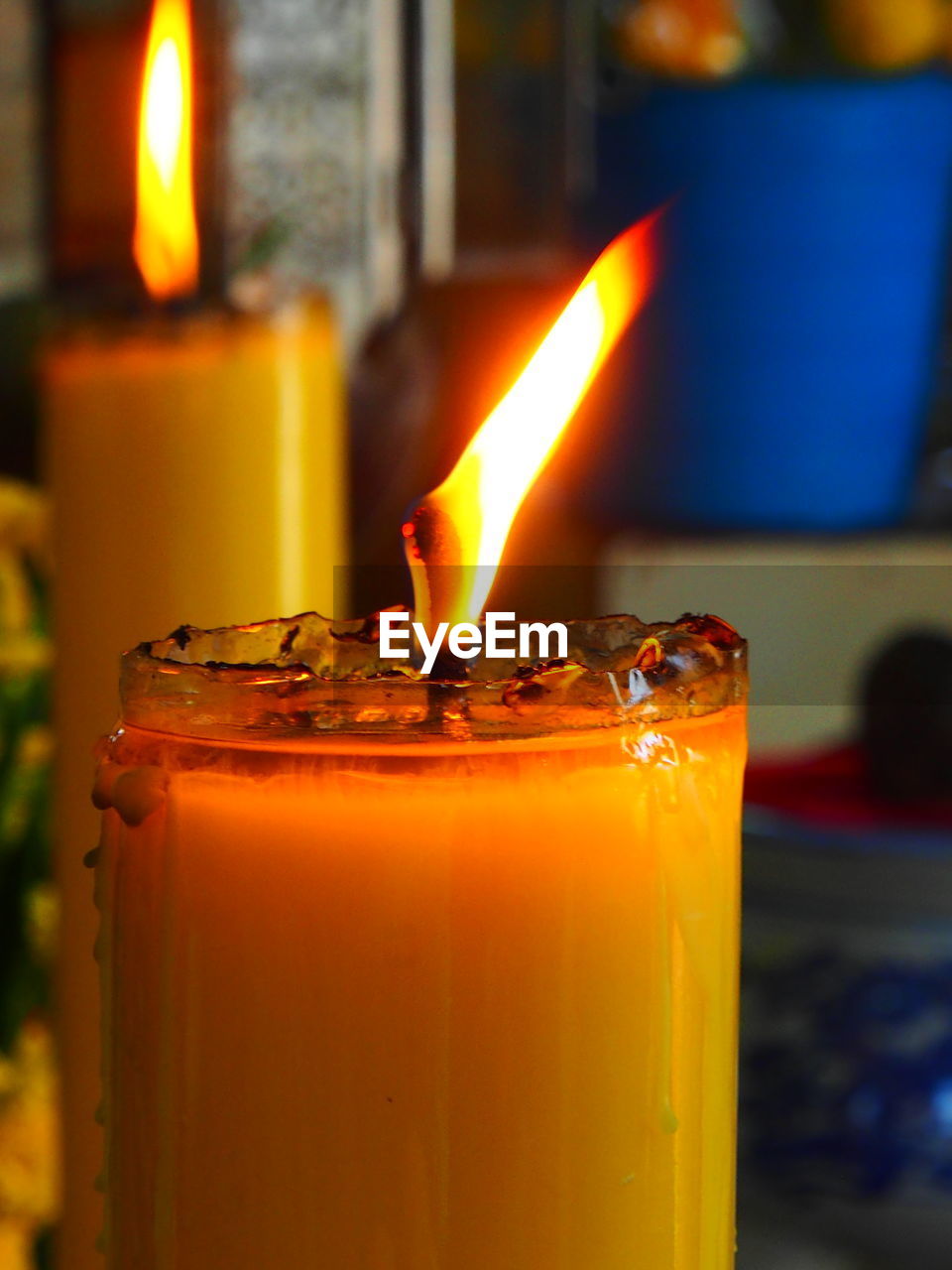 CLOSE-UP OF BURNING CANDLE ON TABLE