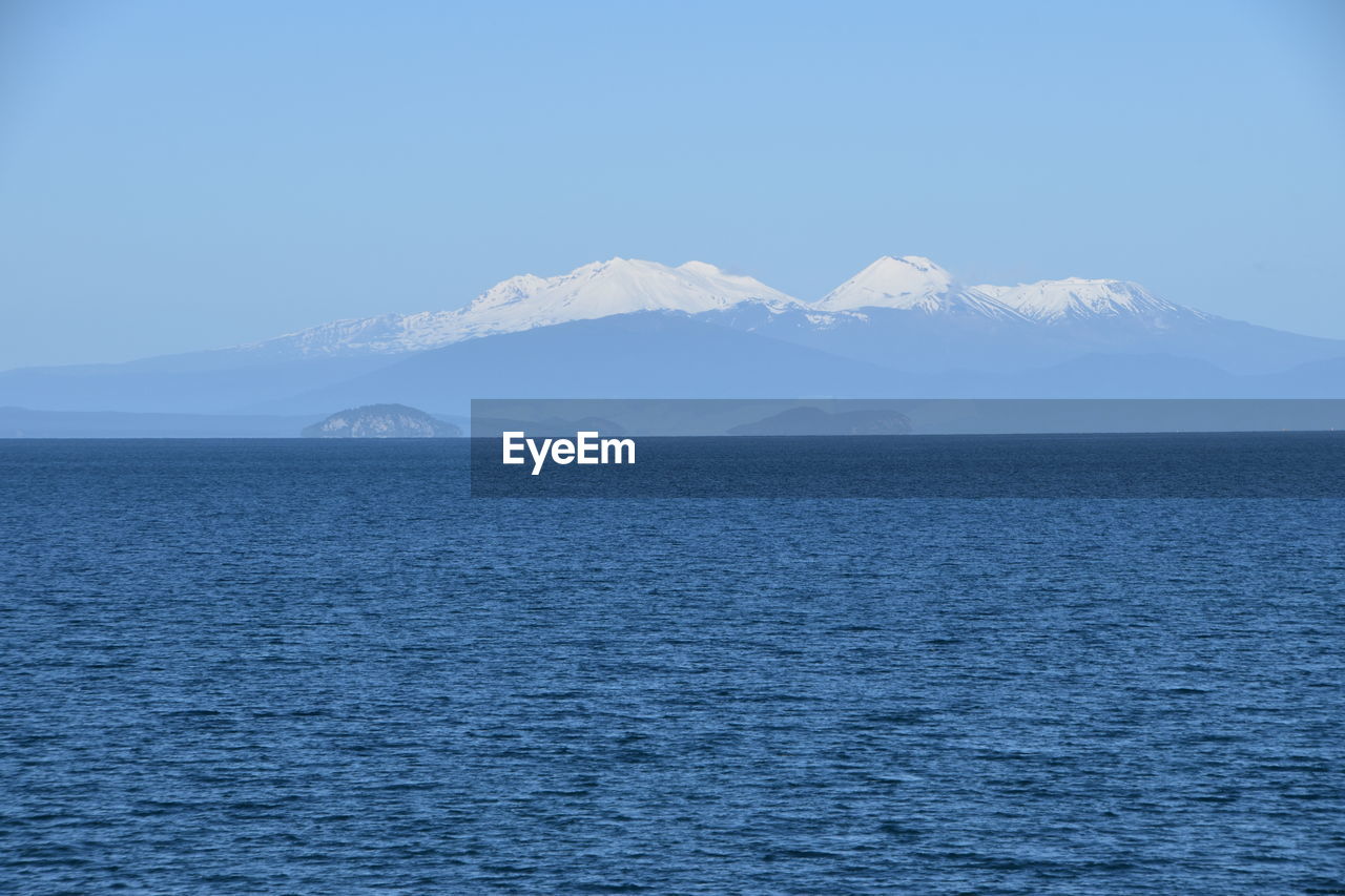 Scenic view of sea and mountains against blue sky
