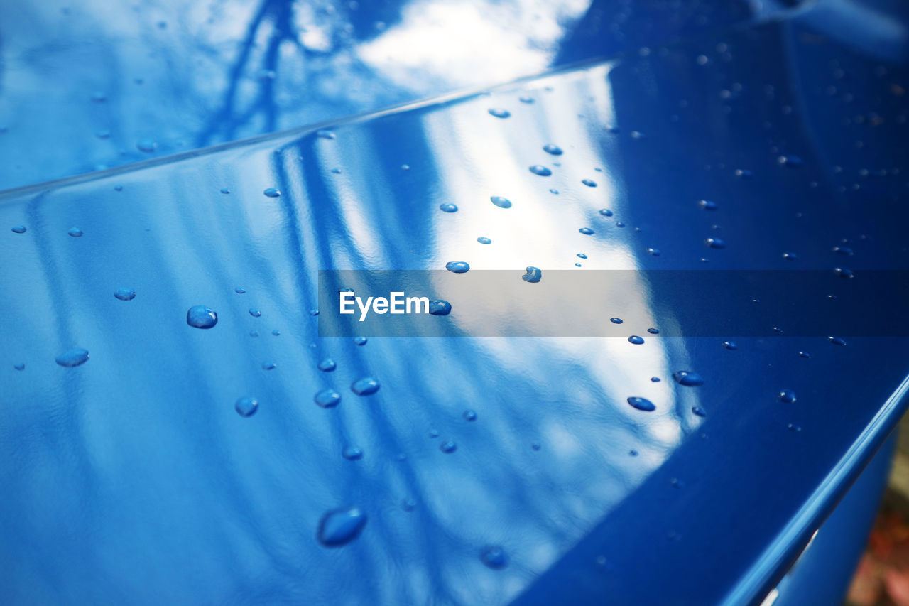 FULL FRAME SHOT OF WATER DROPS ON BLUE SURFACE