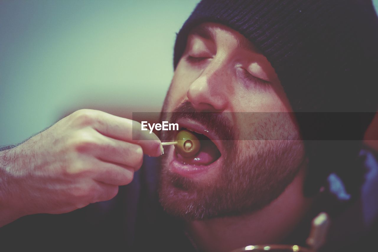 Close-up of man eating olive