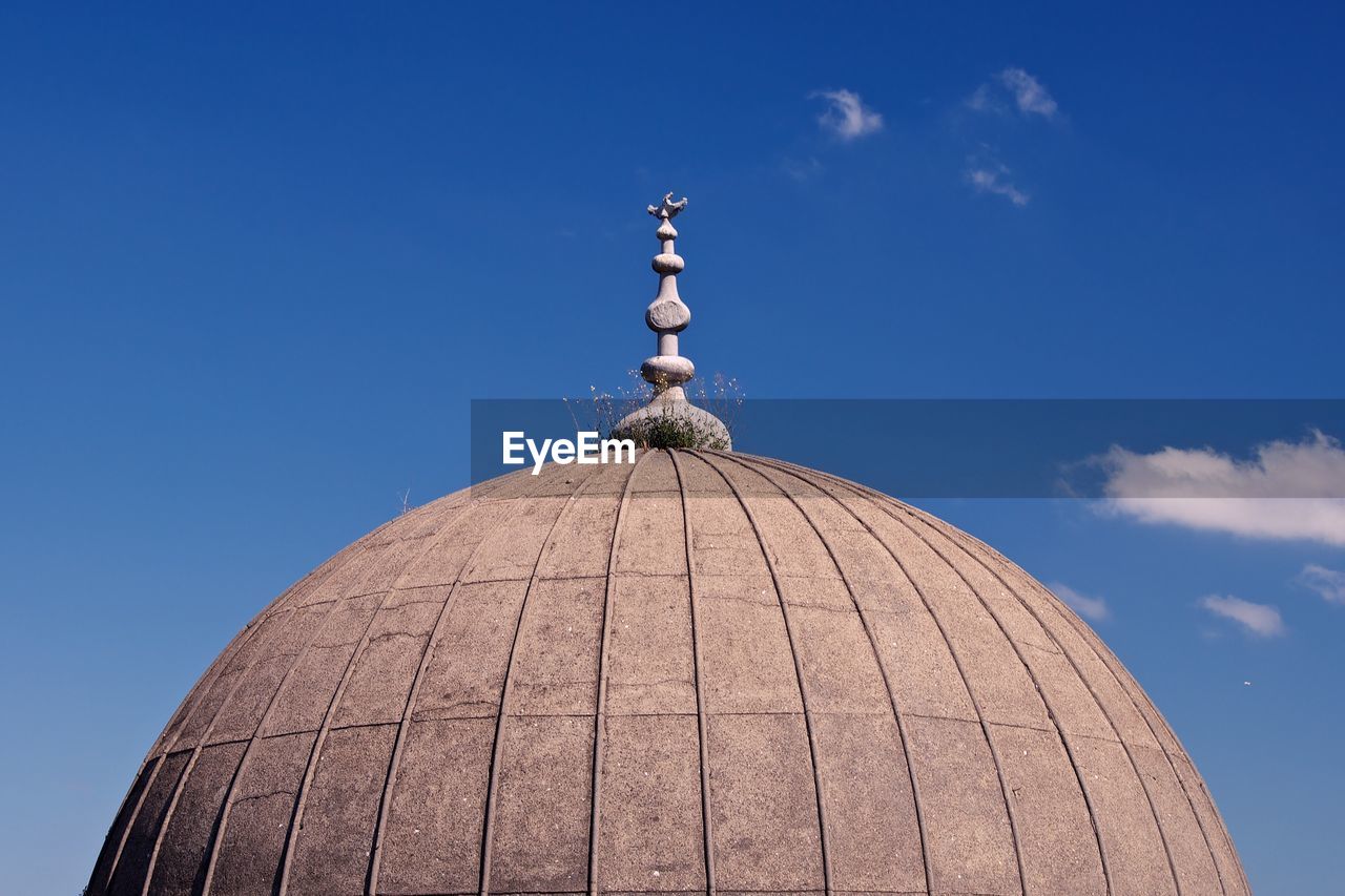 Weathered mosque dome against sky