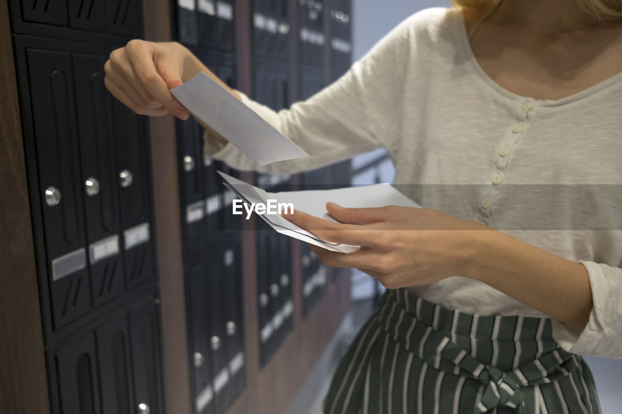 Midsection of woman holding paper in locker room