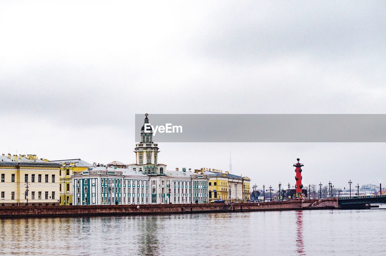 View of buildings at waterfront against cloudy sky