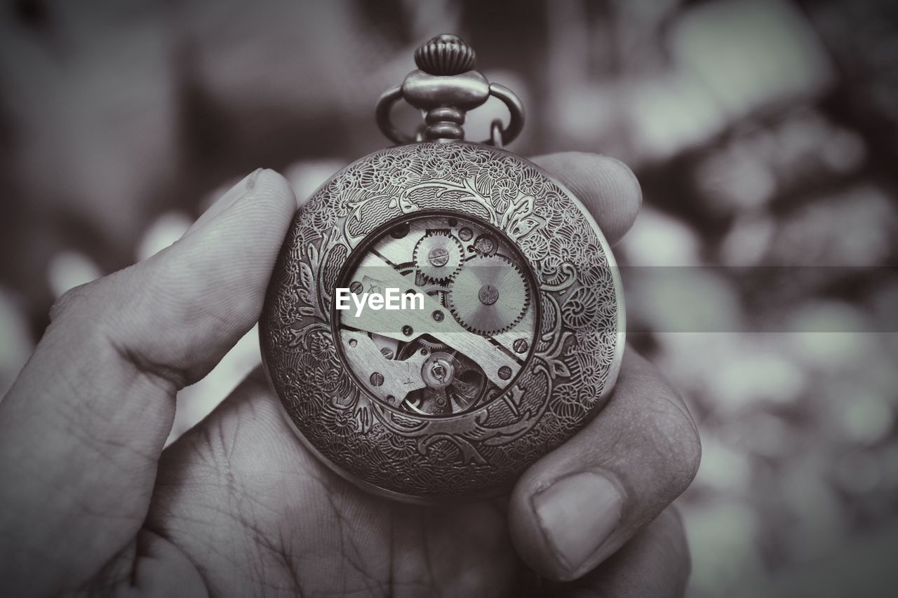 Cropped image of hand holding antique pocket watch