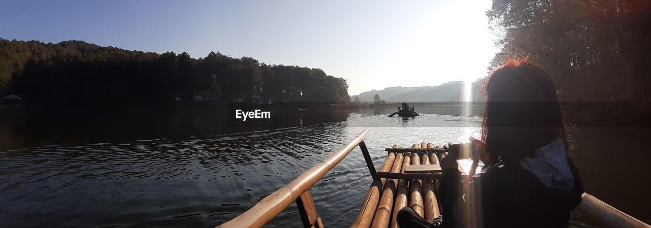 Rear view of woman on lake against sky