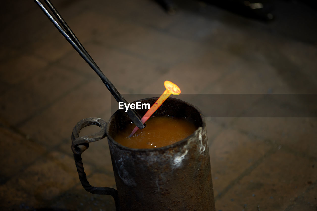 Blacksmith with working tools puts a hot melal nail in the water