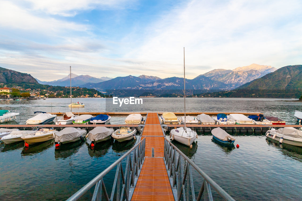 A harbour with boats and pier on lake of como, lombardy, italy at sunset