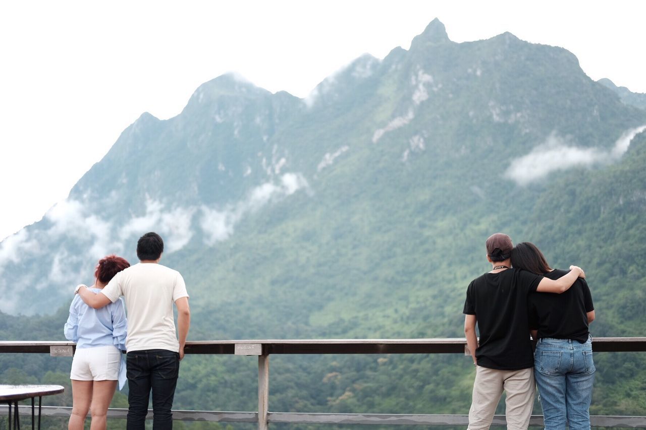 Rear view of couples standing in balcony against mountains