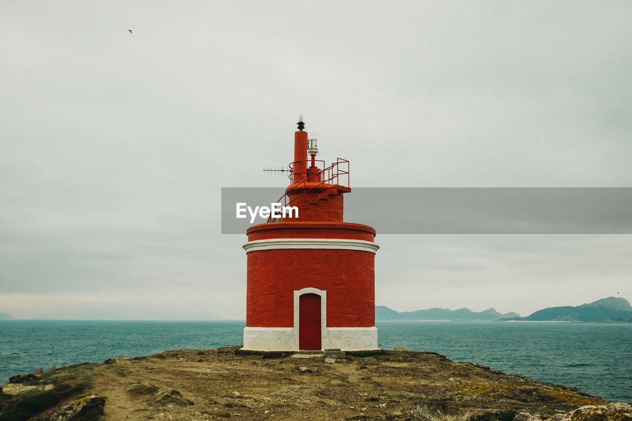 Lighthouse by sea against sky