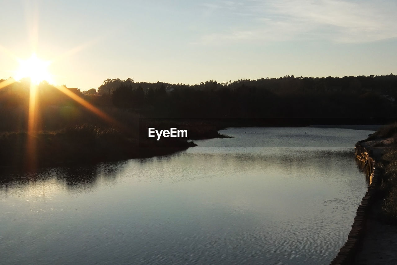 Scenic view of river against sky at sunset