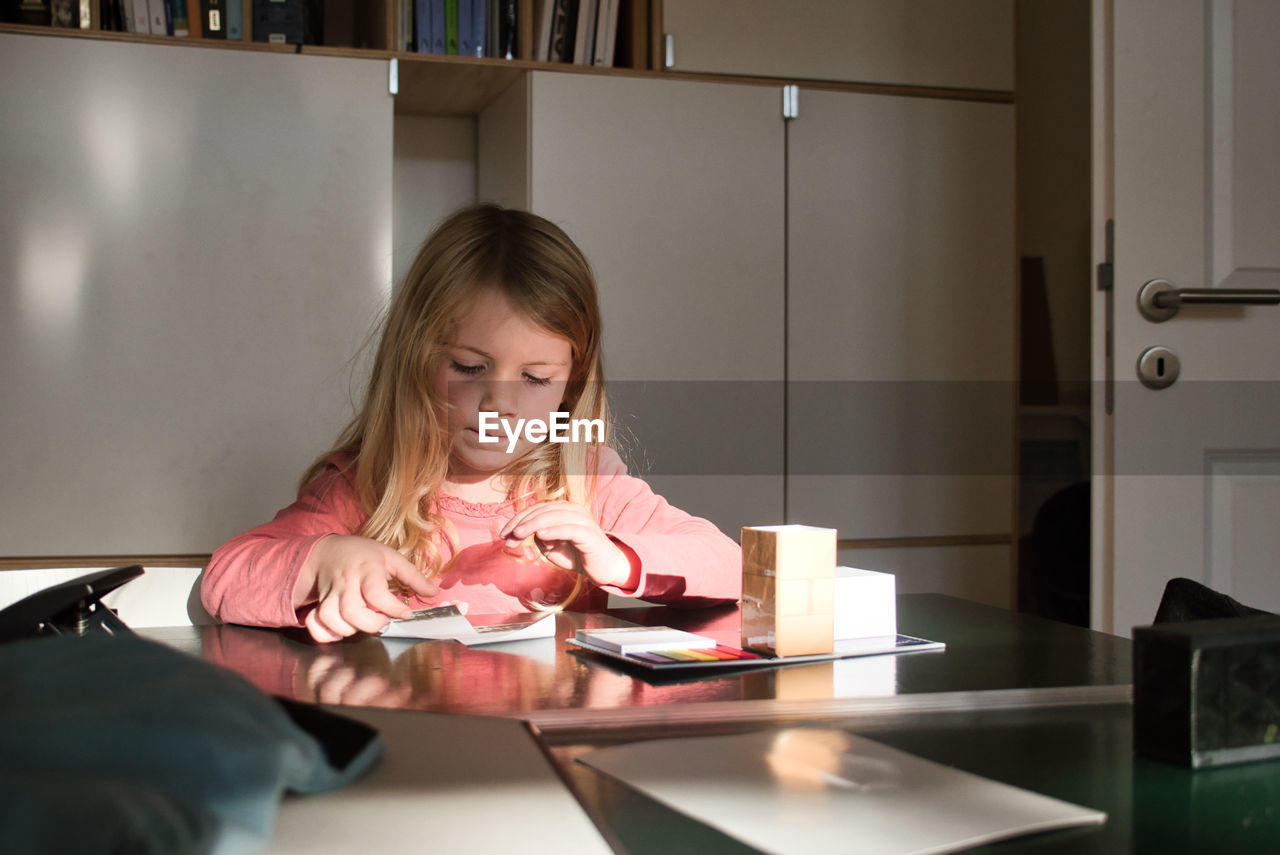 Cute girl sitting by table at home