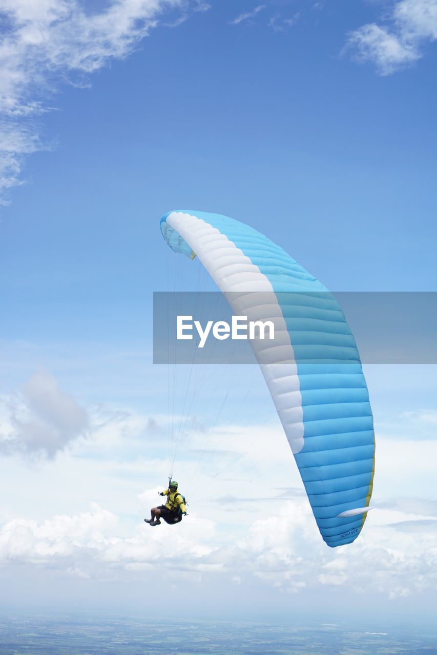 Low angle view of person paragliding against sky