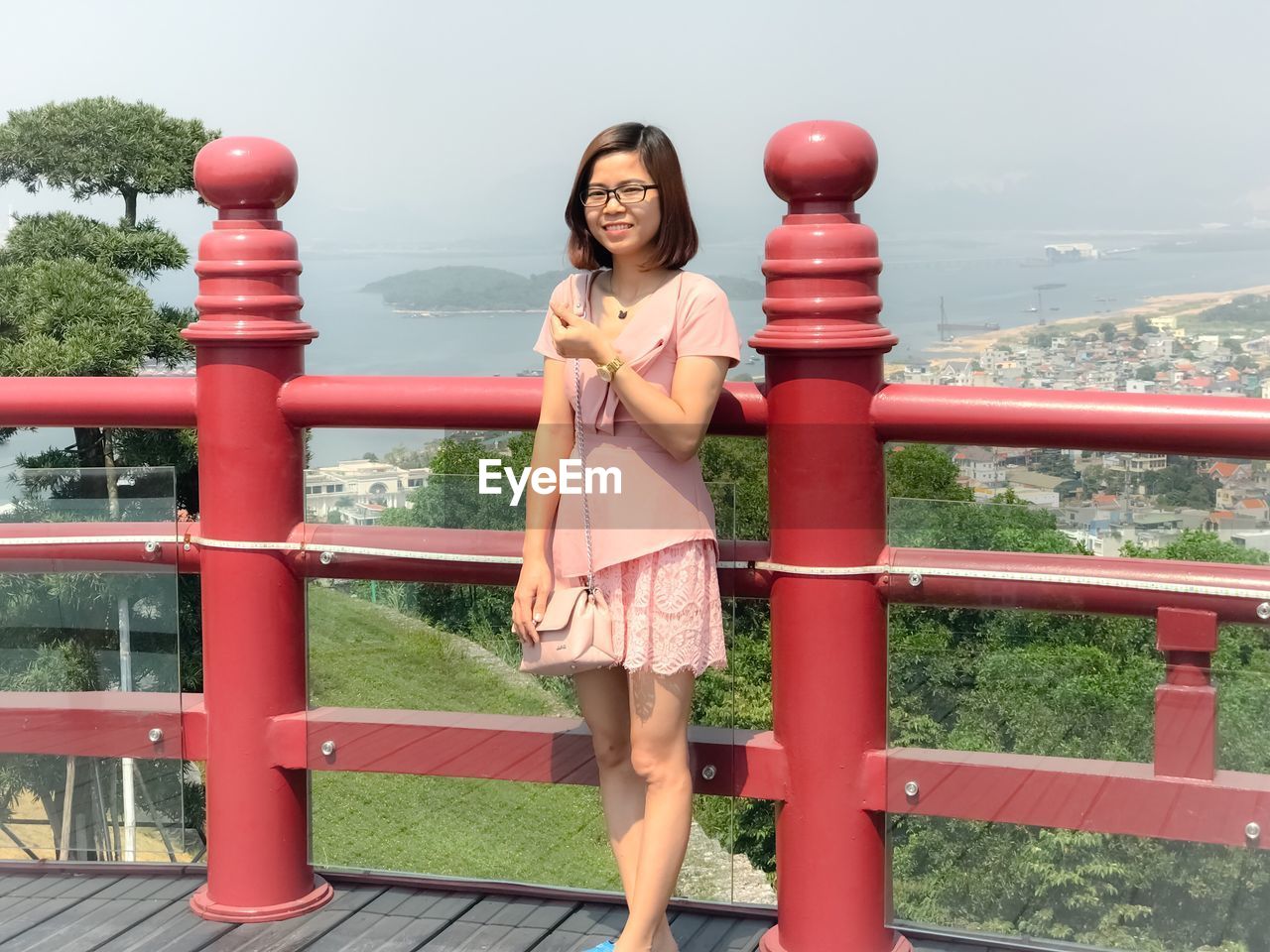 Portrait of young woman standing against railing