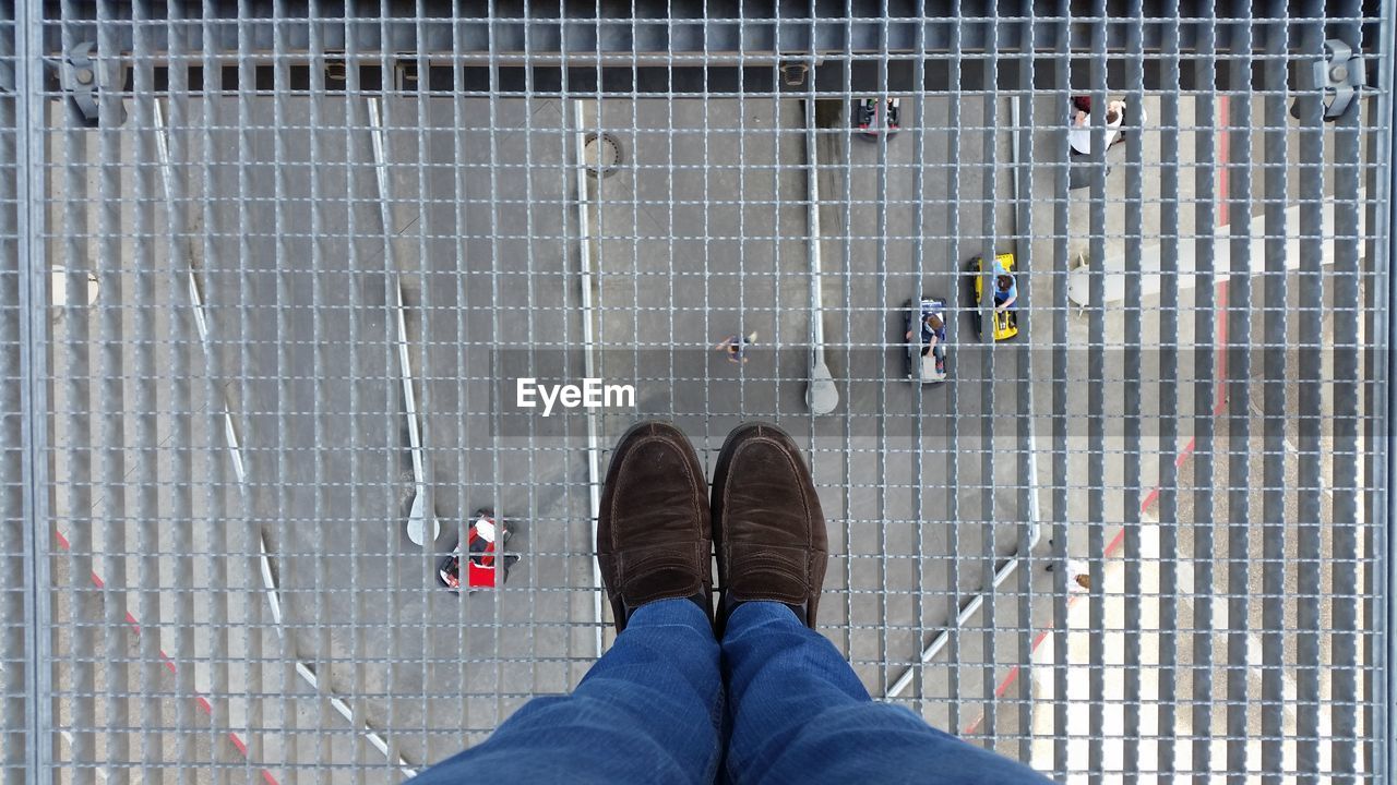 Low section of man standing on metal grate