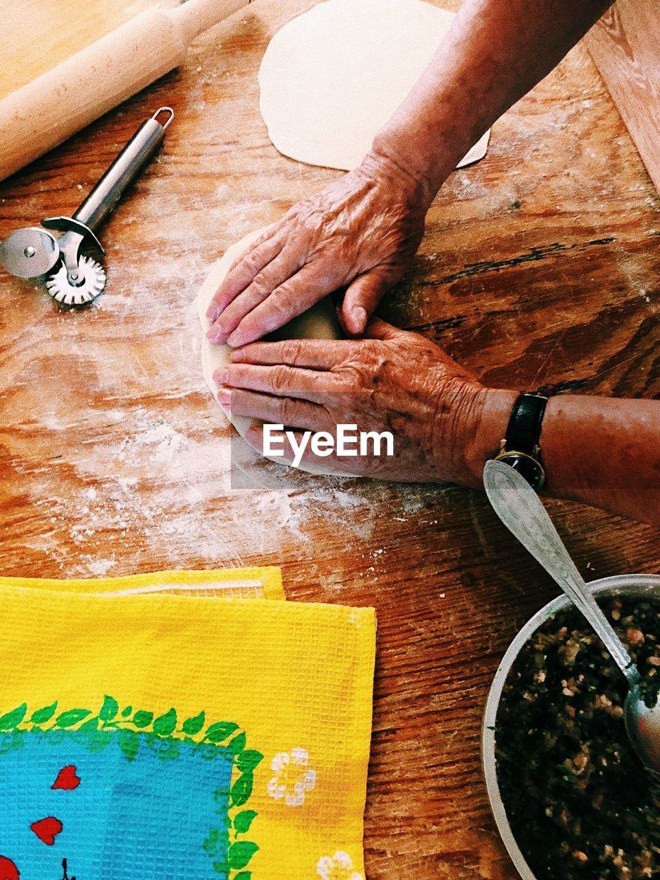 Cropped hands of man kneading dough on wooden table