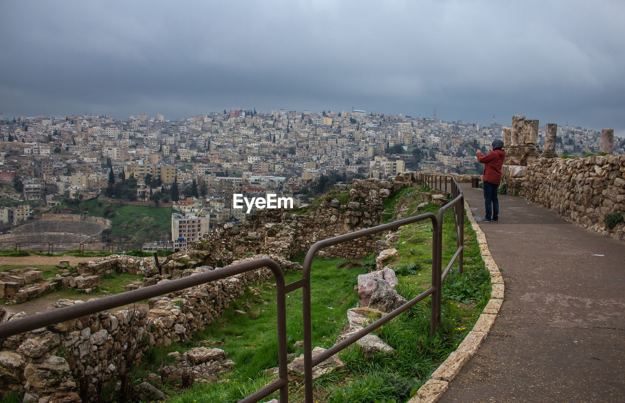 Man standing by railing against cityscape