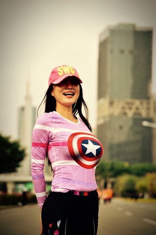 PORTRAIT OF SMILING YOUNG WOMAN STANDING OUTDOORS